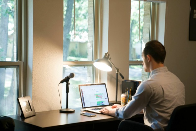 man in white dress shirt sitting on chair using laptop computer