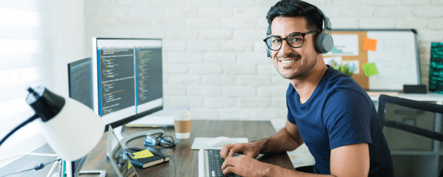 smiling-young-latin-male-freelance-programmer-sitting-with-technology-desk