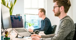 ai for software development: developers working hard - man sitting on chair wearing gray crew-neck long-sleeved shirt using Apple Magic Keyboard