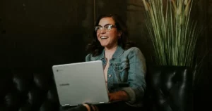 Antibias: female leader laughs while sitting with a silver notebook on lap