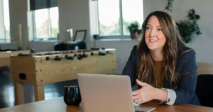 Confident businesswoman reviewing data on laptop at modern office desk. Seeking top talent? Optimize compensation strategies.