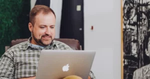 developer guide: man smiling and using MacBook on his lap