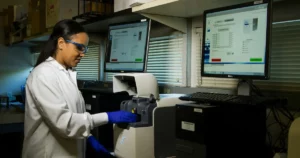 Healthcare Software Teams: woman standing in a lab, using DNA Genotyping and Sequencing machines and apps