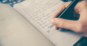 Handwriting a checklist in a notebook, symbolizing the creation of a personal learning and development plan.