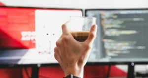 managing remote-first teams: person working from home, holding clear drinking glass with beverage inside