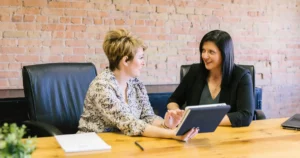 Two female recruiters collaboratively reviewing resumes, symbolizing teamwork in optimizing a recruitment funnel.