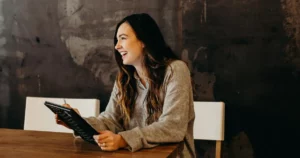 Tech recruiter holding a notebook smiles at candidate, symbolizing a successful talent acquisition pipeline