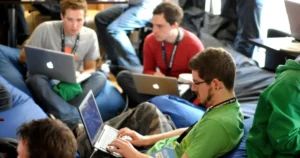 tech talent development: man sitting on blue bean bag using laptop during a tech event.